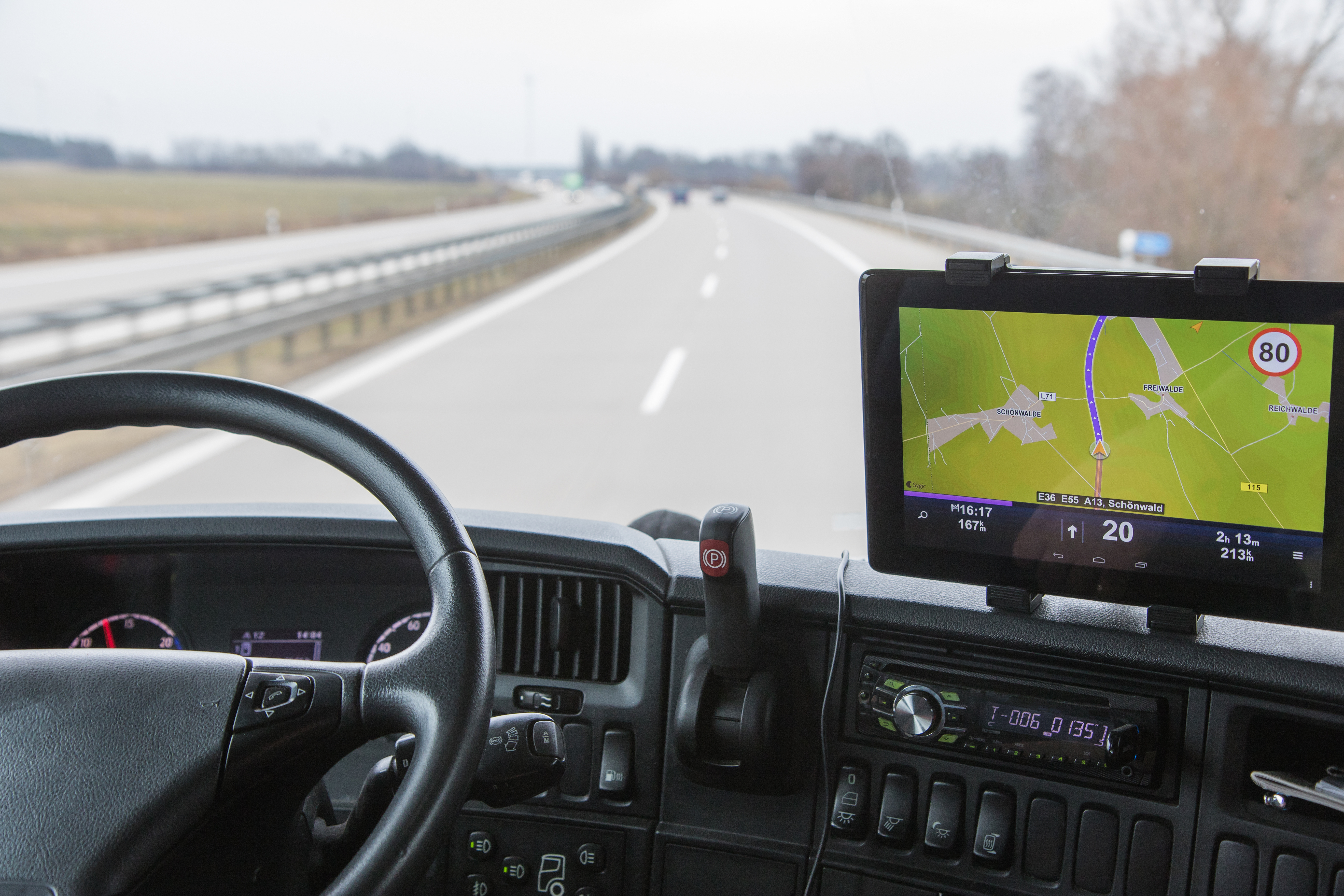 View of highway traffic from the truck View of highway traffic through the windshield of the truck cab. Navigation is mounted on the dashboard.
